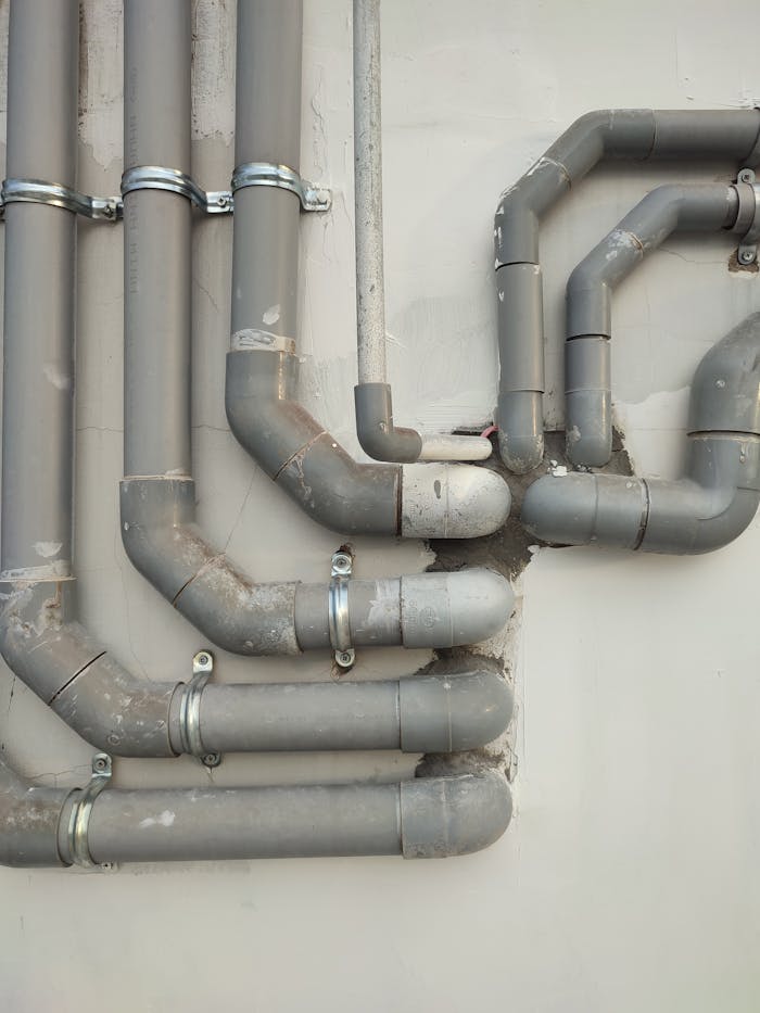 Close-up of interconnected gray metal pipes on an outdoor wall showcasing industrial design.